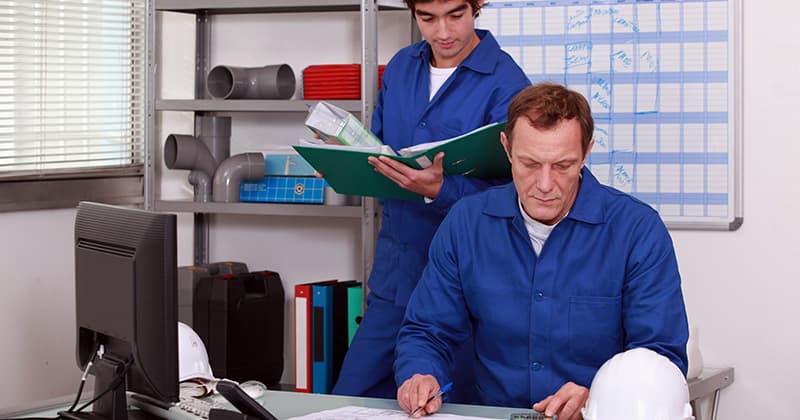 Two plumbers look at schedule in office