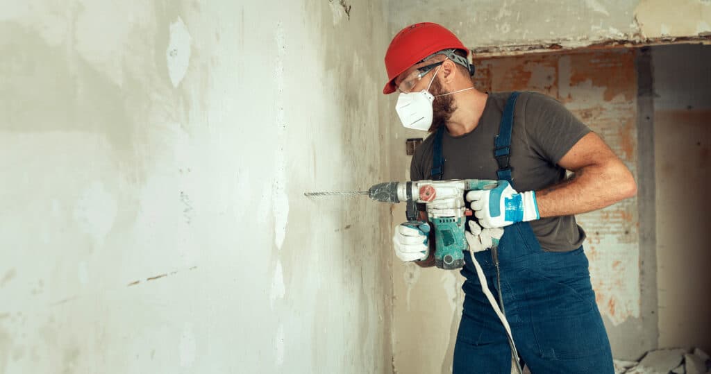 Restoration worker drills into a wall