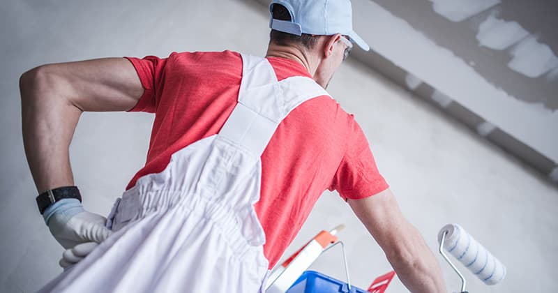 restoration worker holds a rolling paint brush