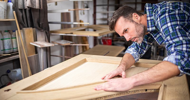 restoration worker lines up a woodworking project